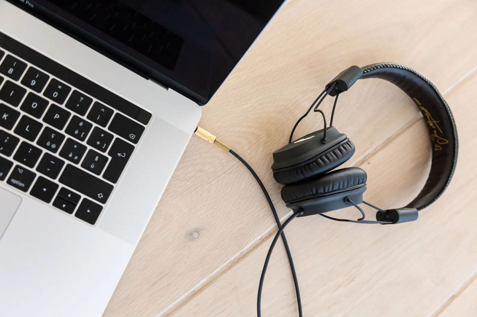 Headphones and a laptop on a wooden desk ready for audio review