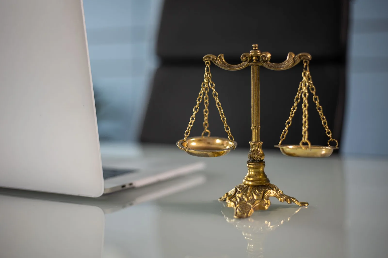 Scales of justice on a desk beside an open laptop