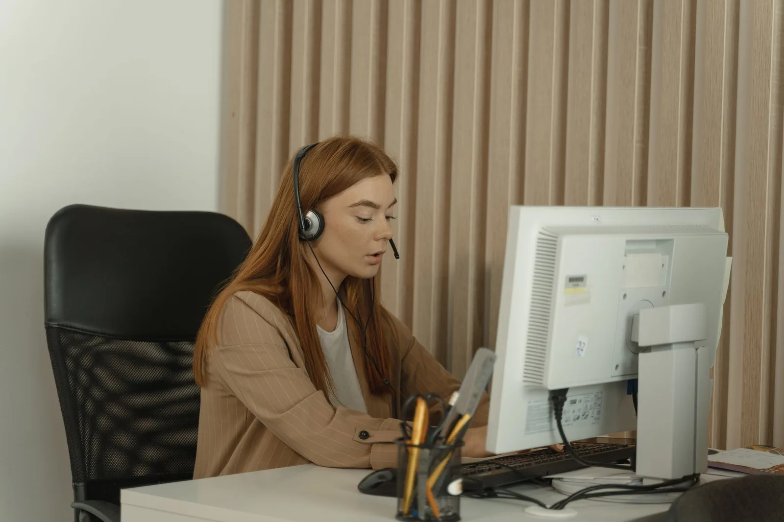 Transcriptionist proofreading on a desktop computer with a headset